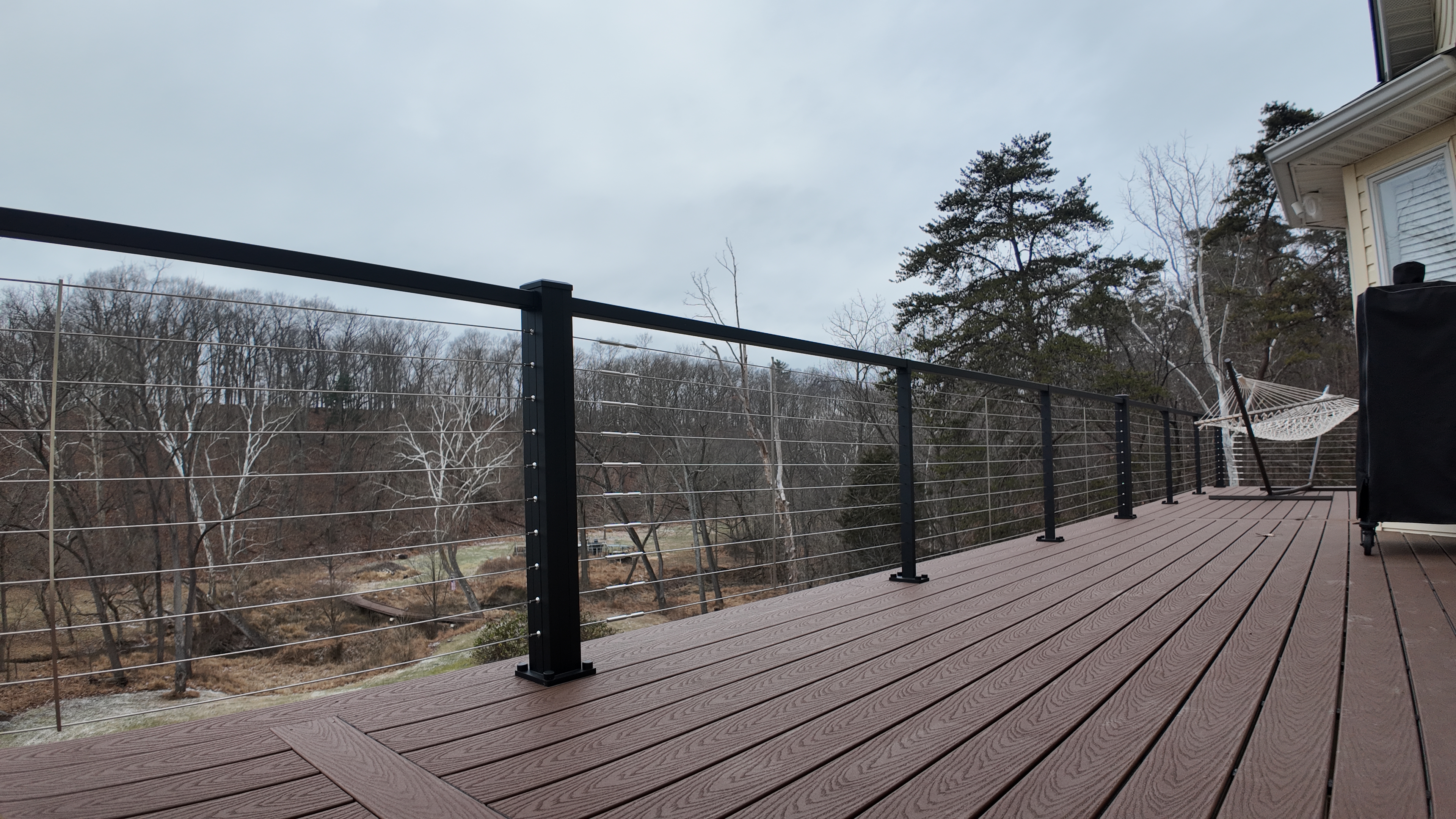 Black cable railing on brown composite deck with wooded view built by Stoneridge in Virginia