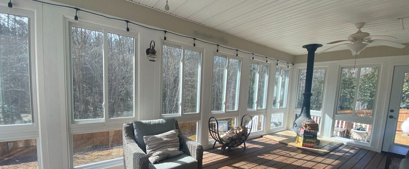 Screened porch interior with motorized screens and string lights by Stoneridge Decks