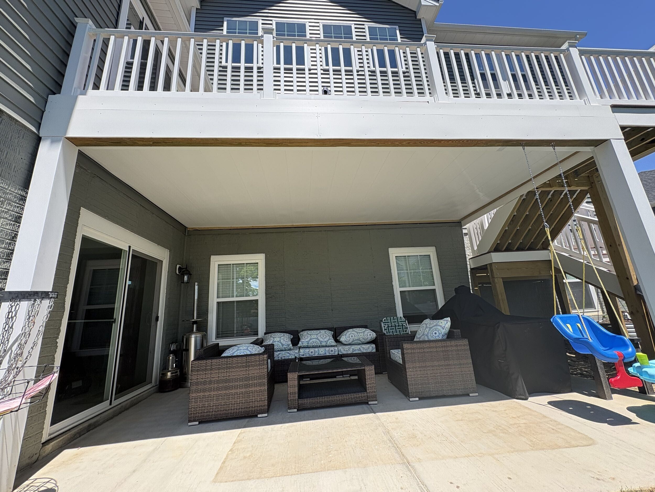 Under deck covered patio with white railing and seating area built by Stoneridge Decks in Virginia